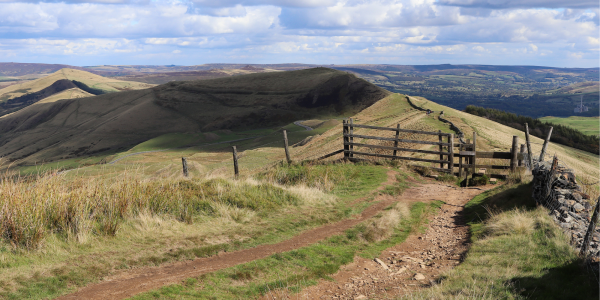 A stile on a path in front of a sweeping landscape